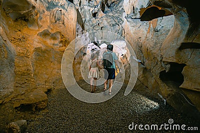 Couple of tourists exploring the cave. The interior of the cave. Touristic hiking route. Concept of excursions and attractions. C Stock Photo